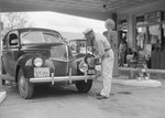 A man polishing his headlights at a Gulf Service Station. by William Garber