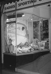 The front window of Hodgin's Store (electronics and sporting goods) in Woodstock, Va. Window advertises National Baseball Week, April 3-10. by William Garber