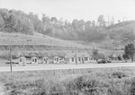 Ike's Tourist Camp, roadside cabins with a Texaco service station, distant front view. by William Garber