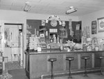 Inside of a diner or store, view of the counter with a door to a kitchen in the background. by William Garber