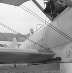 A young boy sitting in the cockpit of a plane, presumably Jack Reynold's plane by William Garber