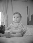 A baby or toddler sitting up on a bed by William Garber