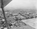 A number of large buildings, probably of the Eastern Mennonite University campus, with the plane obstructing the view. Harrisonburg, Va. by William Garber