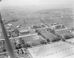 A number of large buildings, probably of the Eastern Mennonite University campus, with the plane obstructing the view. Harrisonburg, Va. by William Garber