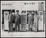 Four men posing outside of Moyer's Motor Company, next to an Esso motor oil display by William Garber