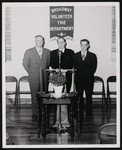 Broadway Volunteer Fire Department, possibly an open house. Three men posing behind a podium by William Garber