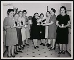 Nine women posing in a kitchen at the Broadway Volunteer Fire Department, pouring and holding beverages by William Garber
