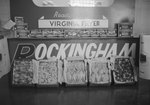 A "Genuine Rockingham Virginia Poultry" display, set up for a fair or other kind of show/presentation. Sponsored by Rockingham Plants in Broadway, Va., and advertising "Ready to Cook Virginia Fryer". Close up of the different cuts of meat at the foot of the display. by William Garber
