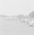 A number of private auotmobiles parked in a field by William Garber