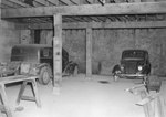 Two private vehicles parked inside of a garage or shop by William Garber