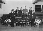 A group of firemen/officers posing in front of a fire truck with flower bouquets on either side and a large sign that says "New Market Fire Dept. New Market Va." by William Garber