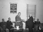 Broadway Volunteer Fire Department, possibly an open house; two men in suits about to shake hands behind a podium by William Garber