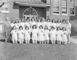 Timberville (High) School, a women's sports team in uniform posing with their coach in front of the school; possibly a tennis team. by William Garber