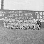 Team photo of the Front Royal male baseball team (probably Front Royal Cardinals of the Valley Baseball League), taken in front of a baseball field's fence which advertises for Woodstock businesses by William Garber