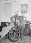 A man in a wheelchair holding a large trophy belonging to the Timberville Hatchery baseball team by William Garber