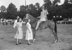 Timberville Horse Show, a man riding a horse with a ribbon, and two girls standing next to him by William Garber