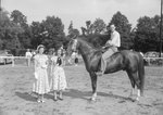 Timberville Horse Show, two young women standing next to a man on a horse with a ribbon by William Garber