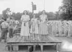 Timberville Horse Show, three women standing on a platform holding a bridle and various other items by William Garber