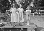 Timberville Horse Show, two young women and a young girl standing on a platform holding a bridle and various other items by William Garber