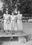 Timberville Horse Show, three young women standing on a platform holding horse bridles, ribbons, and a trophy by William Garber