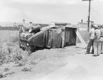 An automobile laying on its side, with the top of the car pictured by William Garber